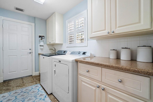 clothes washing area with washer and dryer and cabinets