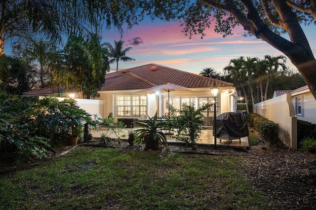 back house at dusk with a yard and a patio