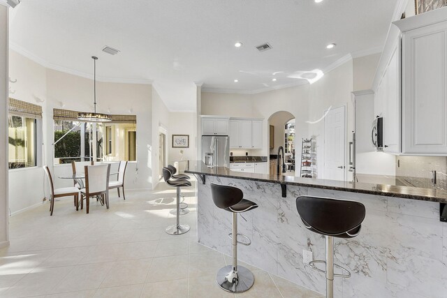 kitchen with pendant lighting, stainless steel appliances, dark stone countertops, and white cabinets