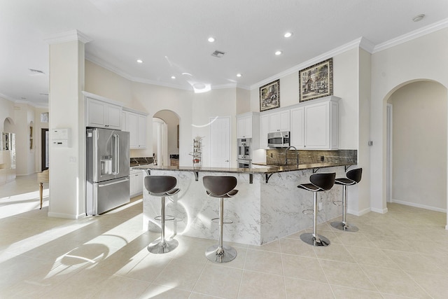 kitchen featuring light tile patterned flooring, appliances with stainless steel finishes, a kitchen breakfast bar, and white cabinets