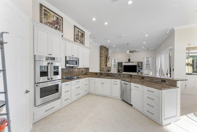 kitchen featuring white cabinetry, stainless steel appliances, kitchen peninsula, and dark stone counters