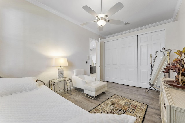 bedroom with crown molding, light wood-type flooring, ceiling fan, and a closet