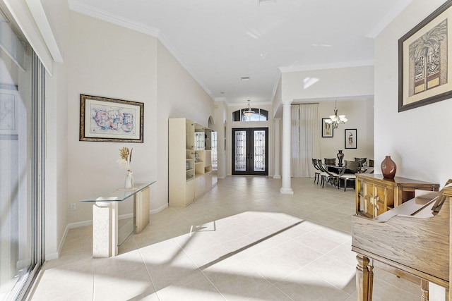 tiled entrance foyer with a chandelier, decorative columns, crown molding, and french doors