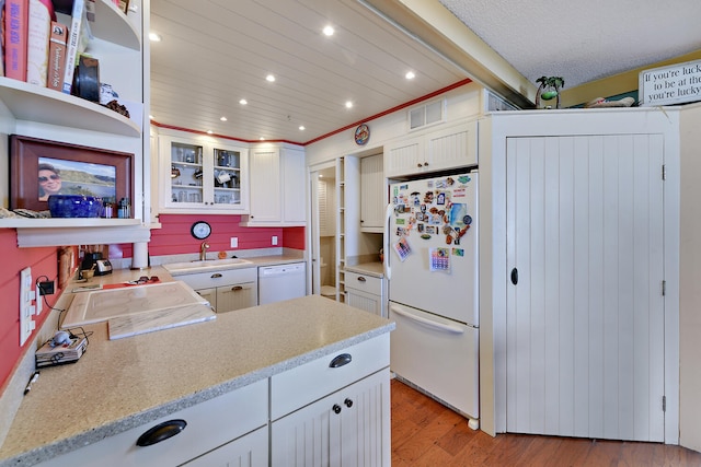 kitchen with white appliances, white cabinets, sink, light hardwood / wood-style floors, and light stone counters