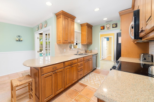 kitchen with light stone countertops, stainless steel appliances, sink, backsplash, and a breakfast bar