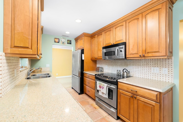 kitchen with light stone countertops, appliances with stainless steel finishes, backsplash, and sink