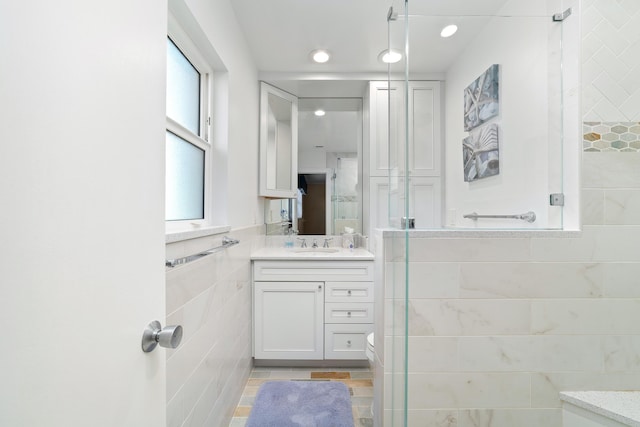 bathroom with tile walls, toilet, vanity, and tile patterned flooring