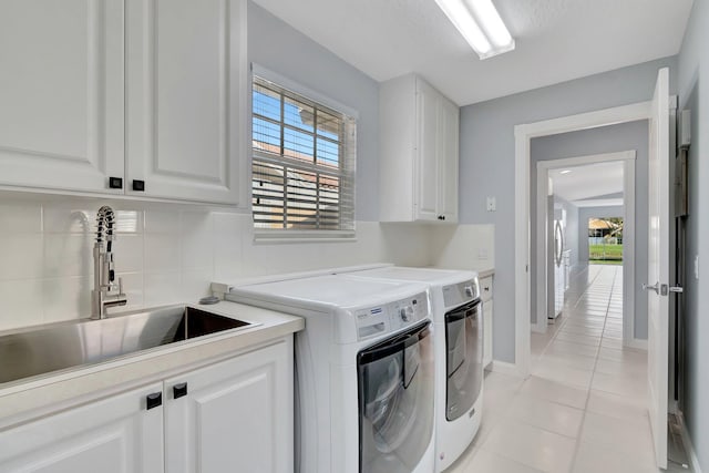 laundry room with cabinets, washing machine and dryer, sink, and light tile patterned floors