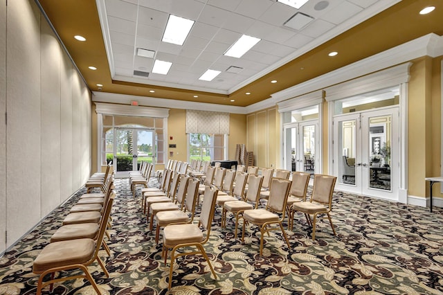 carpeted dining area featuring ornamental molding, french doors, a raised ceiling, and a high ceiling