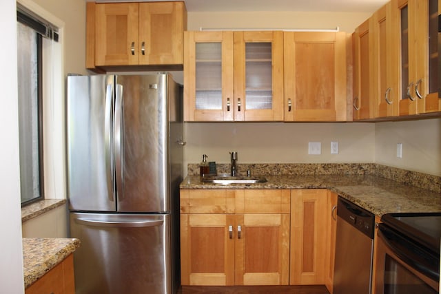 kitchen with light stone counters, appliances with stainless steel finishes, and sink