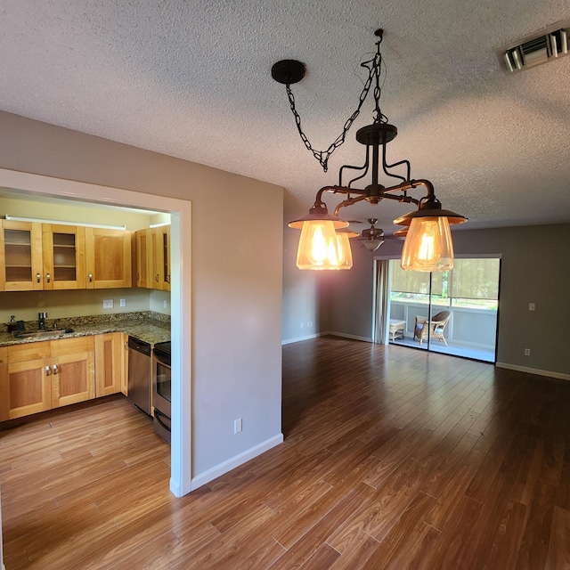 kitchen featuring appliances with stainless steel finishes, pendant lighting, sink, hardwood / wood-style flooring, and a textured ceiling