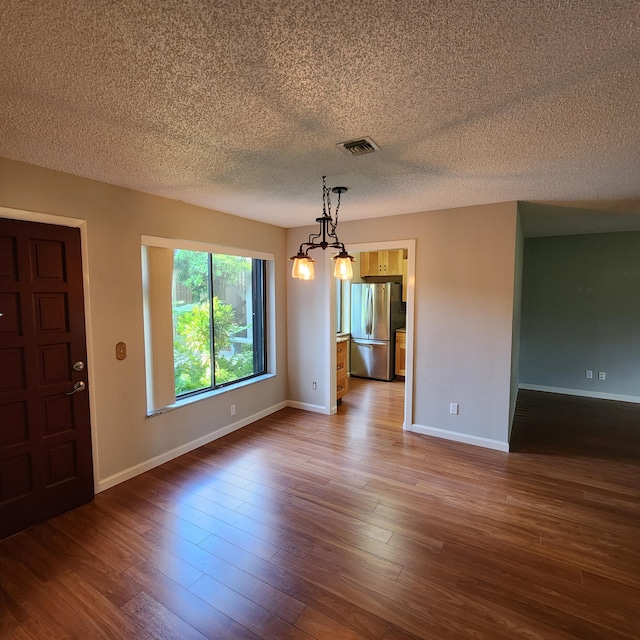 unfurnished dining area with hardwood / wood-style flooring and a textured ceiling