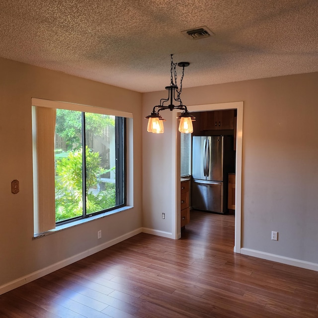 unfurnished dining area with dark wood-type flooring and a textured ceiling