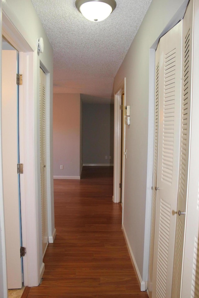 hall featuring dark wood-type flooring and a textured ceiling