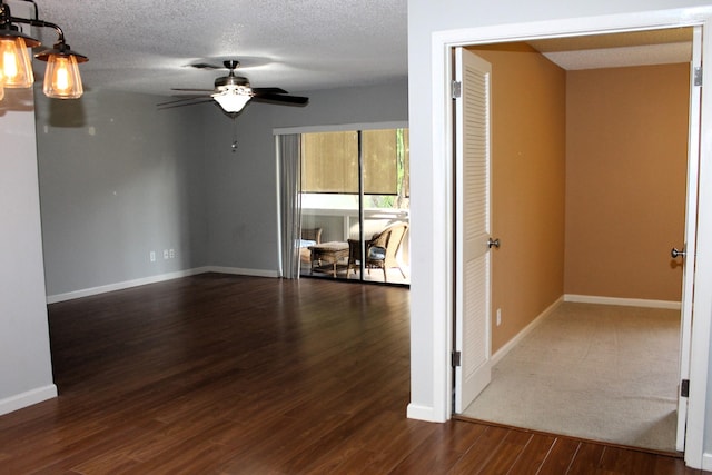 empty room with ceiling fan, dark wood-type flooring, and a textured ceiling