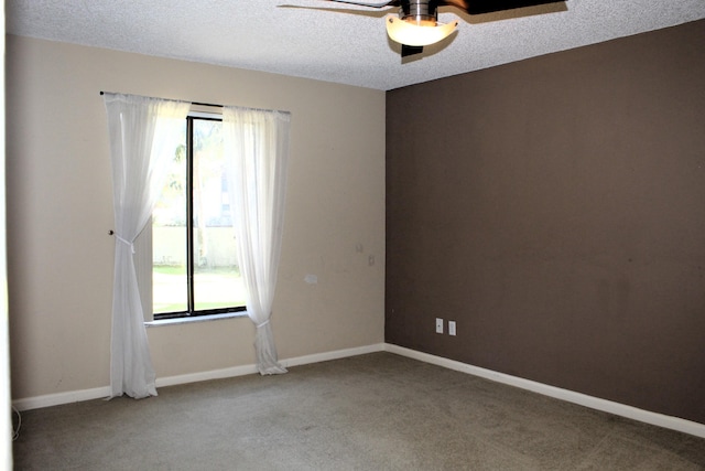 carpeted spare room featuring ceiling fan, a textured ceiling, and a wealth of natural light