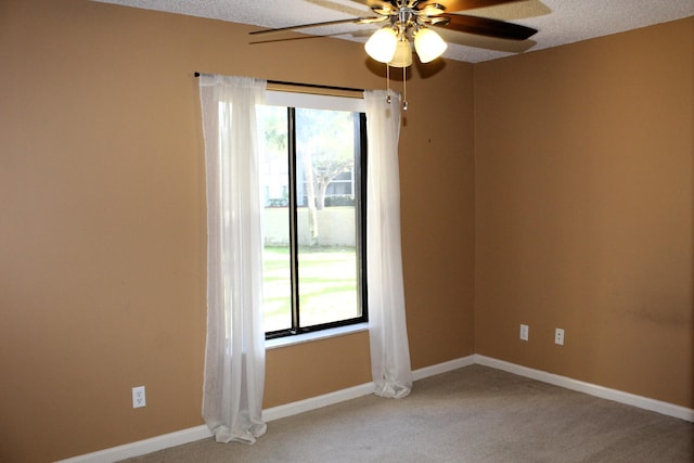 carpeted spare room featuring a textured ceiling, a wealth of natural light, and ceiling fan