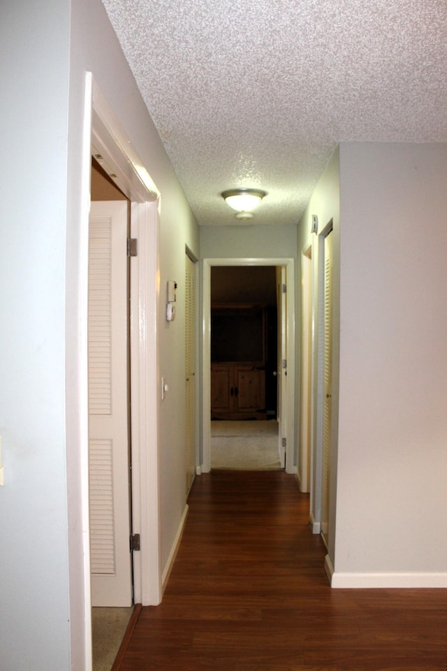 hallway featuring dark hardwood / wood-style floors and a textured ceiling