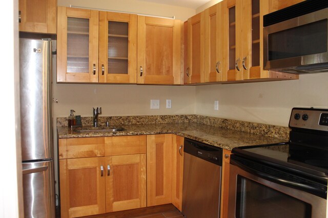 800 NW Fork Rd Unit 2-3, Stuart, FL 34994 - kitchen featuring glass insert cabinets, light wood-type flooring, dark stone countertops, a sink, and stainless steel appliances