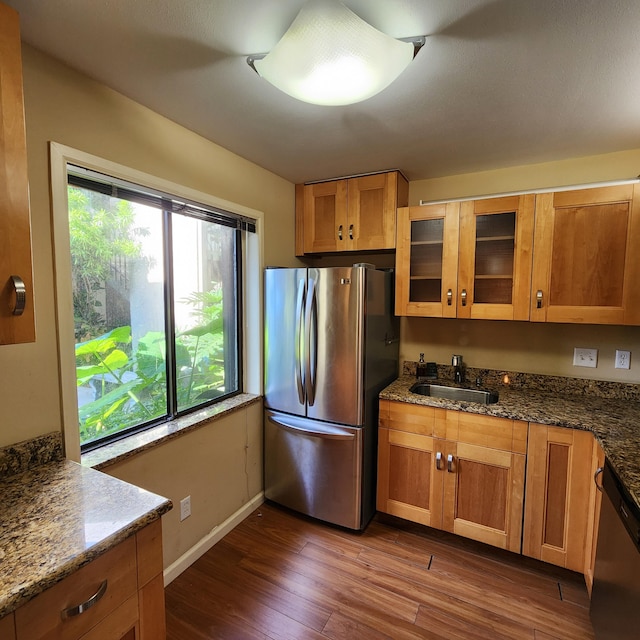 kitchen with stainless steel appliances, sink, dark stone countertops, and dark hardwood / wood-style flooring