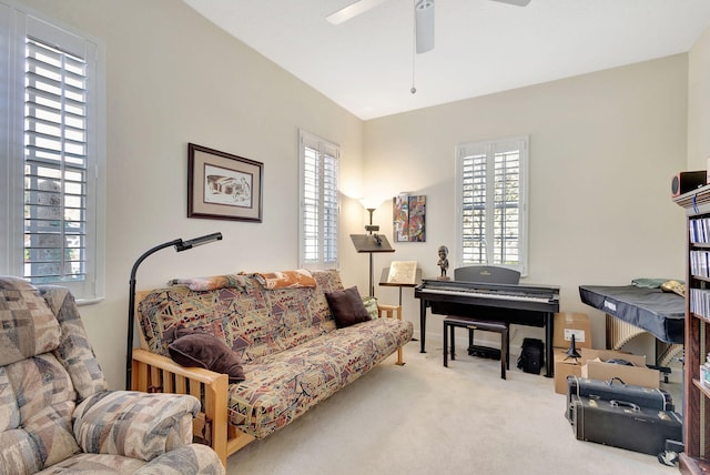 living area with ceiling fan, plenty of natural light, light colored carpet, and lofted ceiling