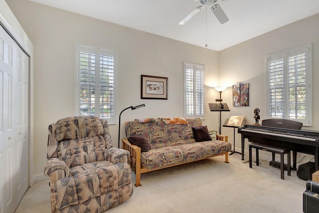 living area featuring light carpet and ceiling fan