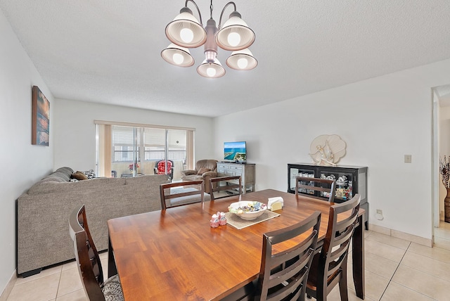 tiled dining area with a chandelier and a textured ceiling