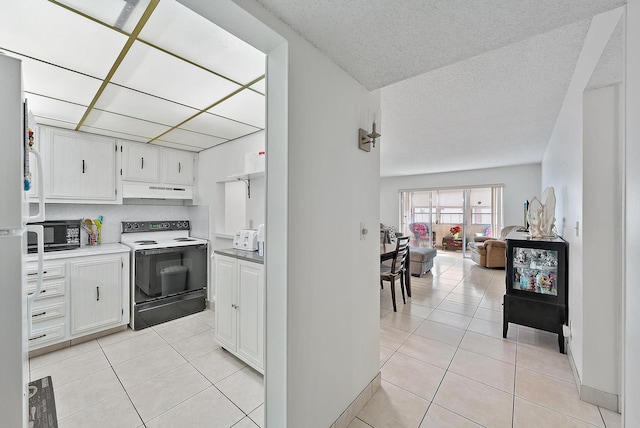 kitchen featuring white range with electric cooktop, light tile patterned flooring, and white cabinets