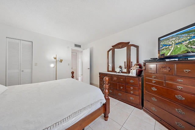 bedroom with light tile patterned floors, a textured ceiling, and a closet