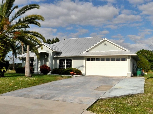 view of front of property with a garage, driveway, metal roof, a front lawn, and stucco siding