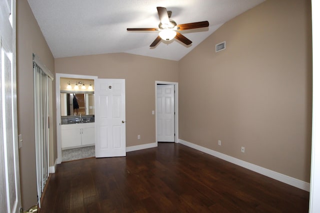 unfurnished bedroom with vaulted ceiling, dark wood-style flooring, a sink, and visible vents