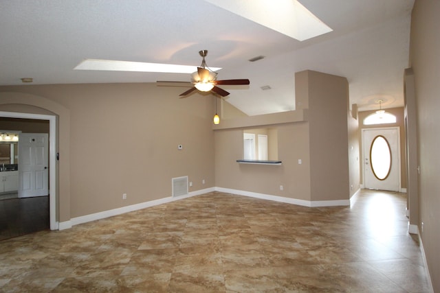 spare room with ceiling fan, lofted ceiling with skylight, visible vents, and baseboards