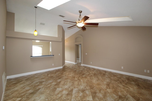 empty room with ceiling fan, vaulted ceiling with skylight, visible vents, and baseboards