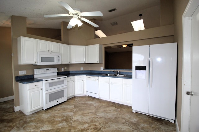 kitchen featuring white appliances, dark countertops, a sink, and white cabinets