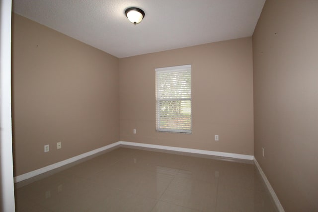 unfurnished room featuring baseboards, a textured ceiling, and tile patterned floors