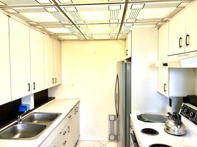 kitchen featuring white cabinets, white range with electric cooktop, sink, stainless steel fridge, and light tile patterned floors