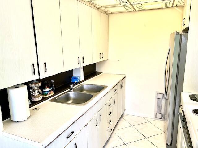 kitchen with white electric range oven, white cabinetry, sink, and stainless steel refrigerator