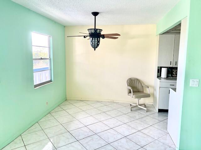 unfurnished dining area with ceiling fan and a textured ceiling