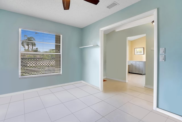 tiled empty room featuring ceiling fan and a textured ceiling