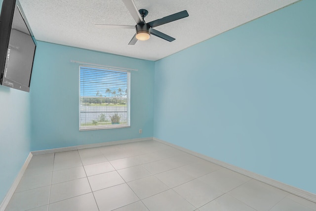 spare room with light tile patterned floors, a textured ceiling, and ceiling fan