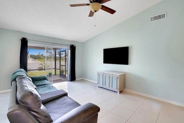 living room featuring ceiling fan, lofted ceiling, a textured ceiling, and light tile patterned floors