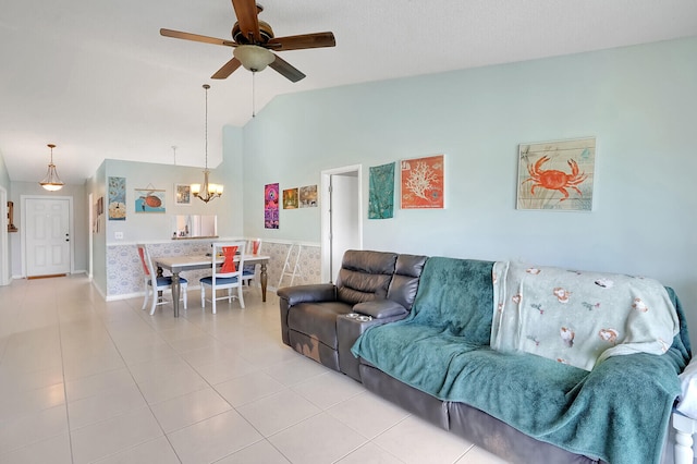 living room featuring tile patterned flooring, ceiling fan with notable chandelier, and vaulted ceiling