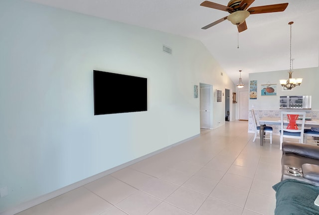 unfurnished living room with ceiling fan with notable chandelier, light tile patterned floors, and vaulted ceiling