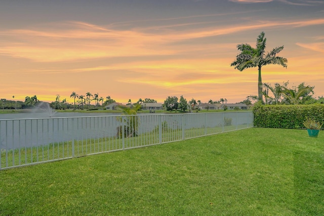 yard at dusk featuring a water view