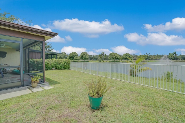 view of yard with a sunroom and a water view