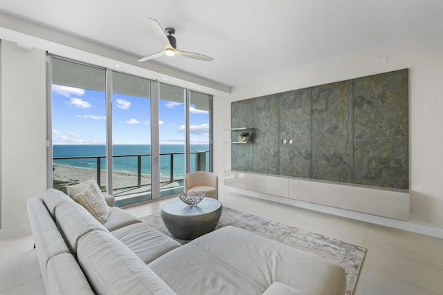 living room with ceiling fan, floor to ceiling windows, a water view, and a view of the beach