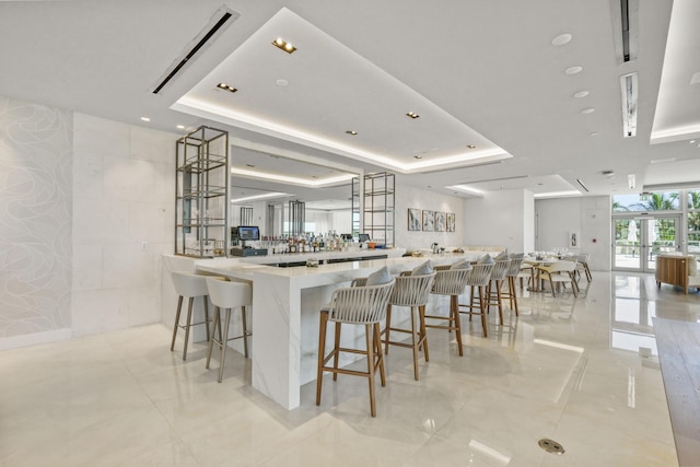 kitchen featuring a tray ceiling, kitchen peninsula, and a breakfast bar