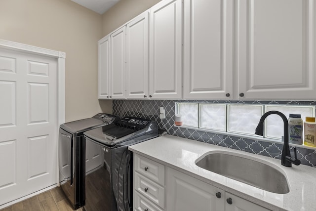 laundry area with washing machine and clothes dryer, sink, cabinets, and light wood-type flooring