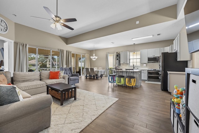 living room featuring a healthy amount of sunlight, ceiling fan, and dark wood-type flooring