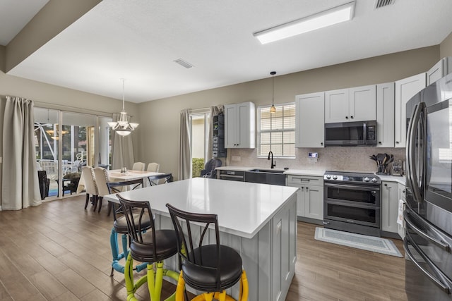 kitchen featuring sink, a kitchen island, stainless steel appliances, and decorative light fixtures